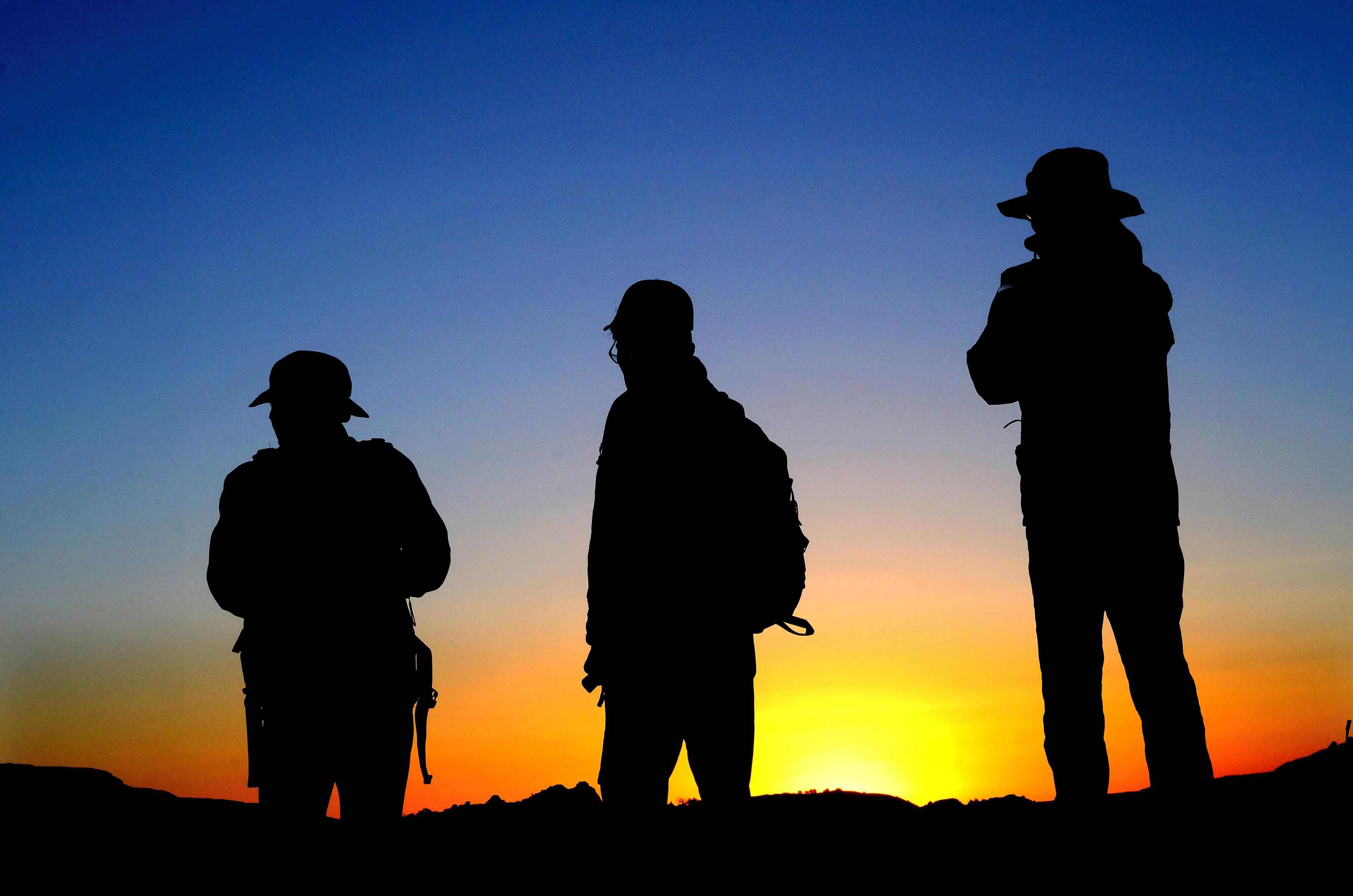 Three hikers silhouetted by the sunset