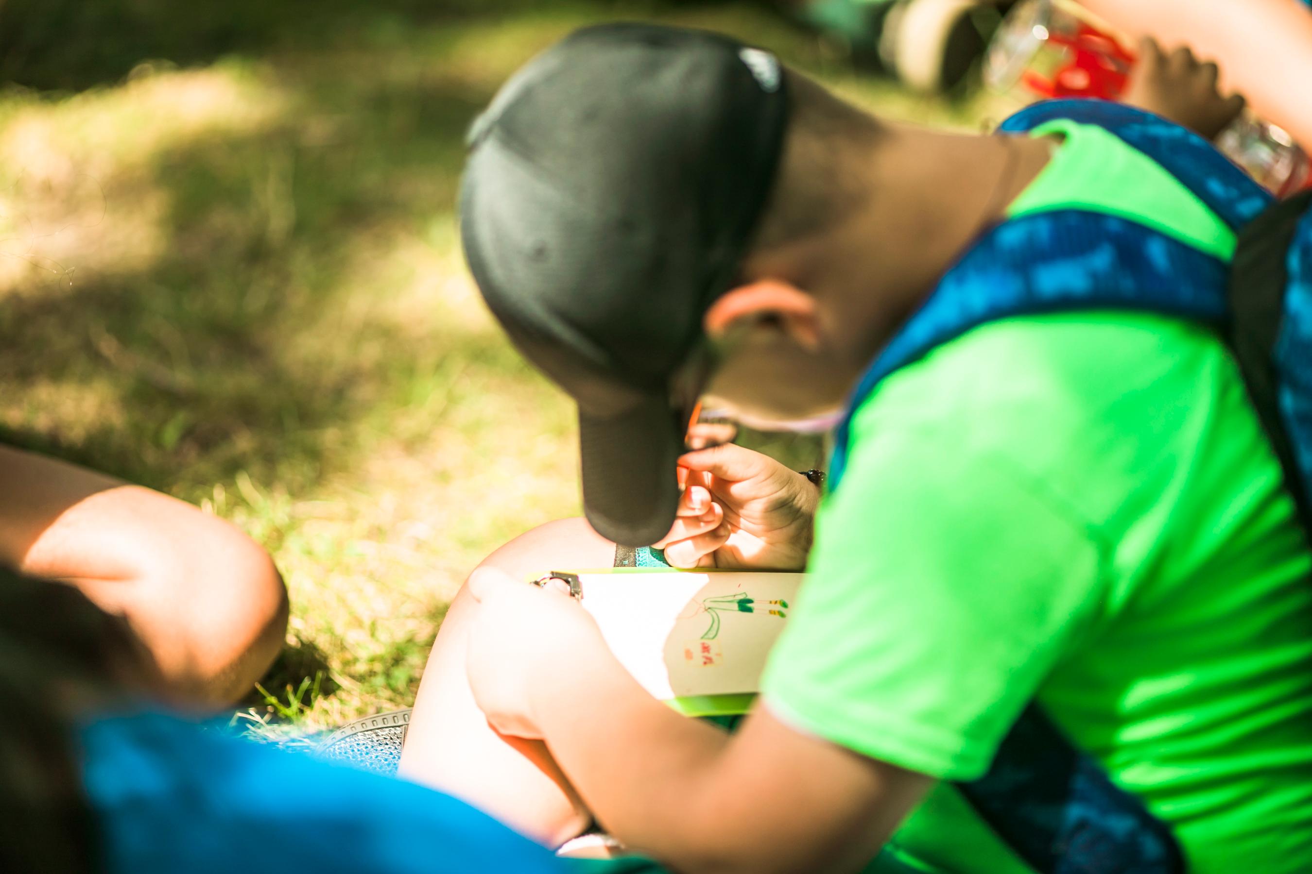 A kid sitting on the ground looking down at an activity he is working on.