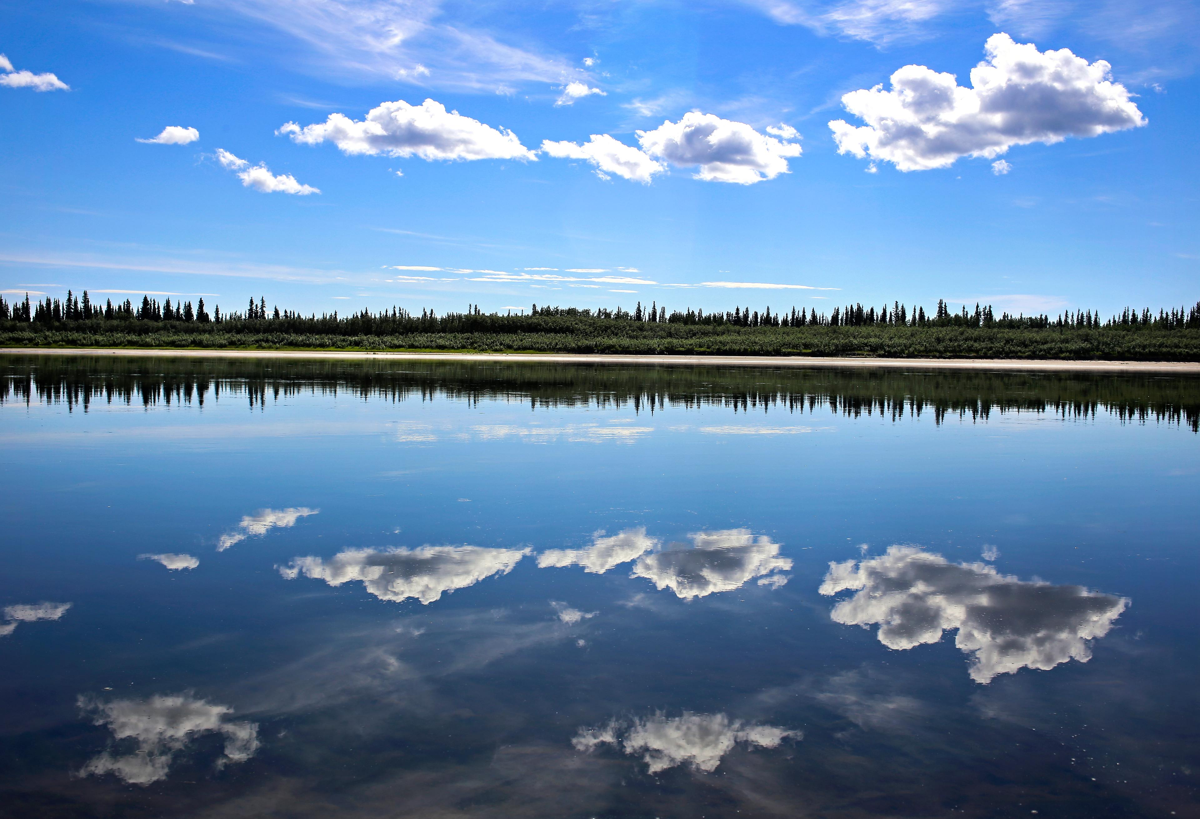 The Kobuk River reflecting the sky and clouds on a calm day.