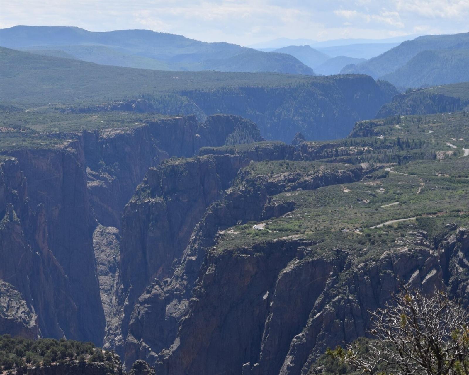 Green and blueish canyon cliffs with mountains in the background