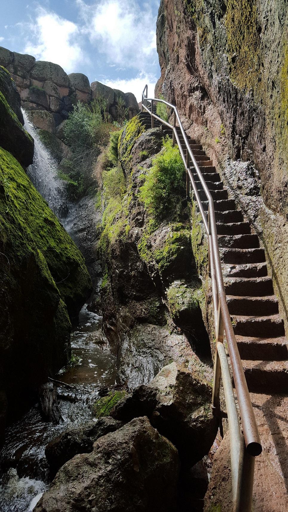 Narrow rock staircase edged out of rock wall in a narrow rock canyon