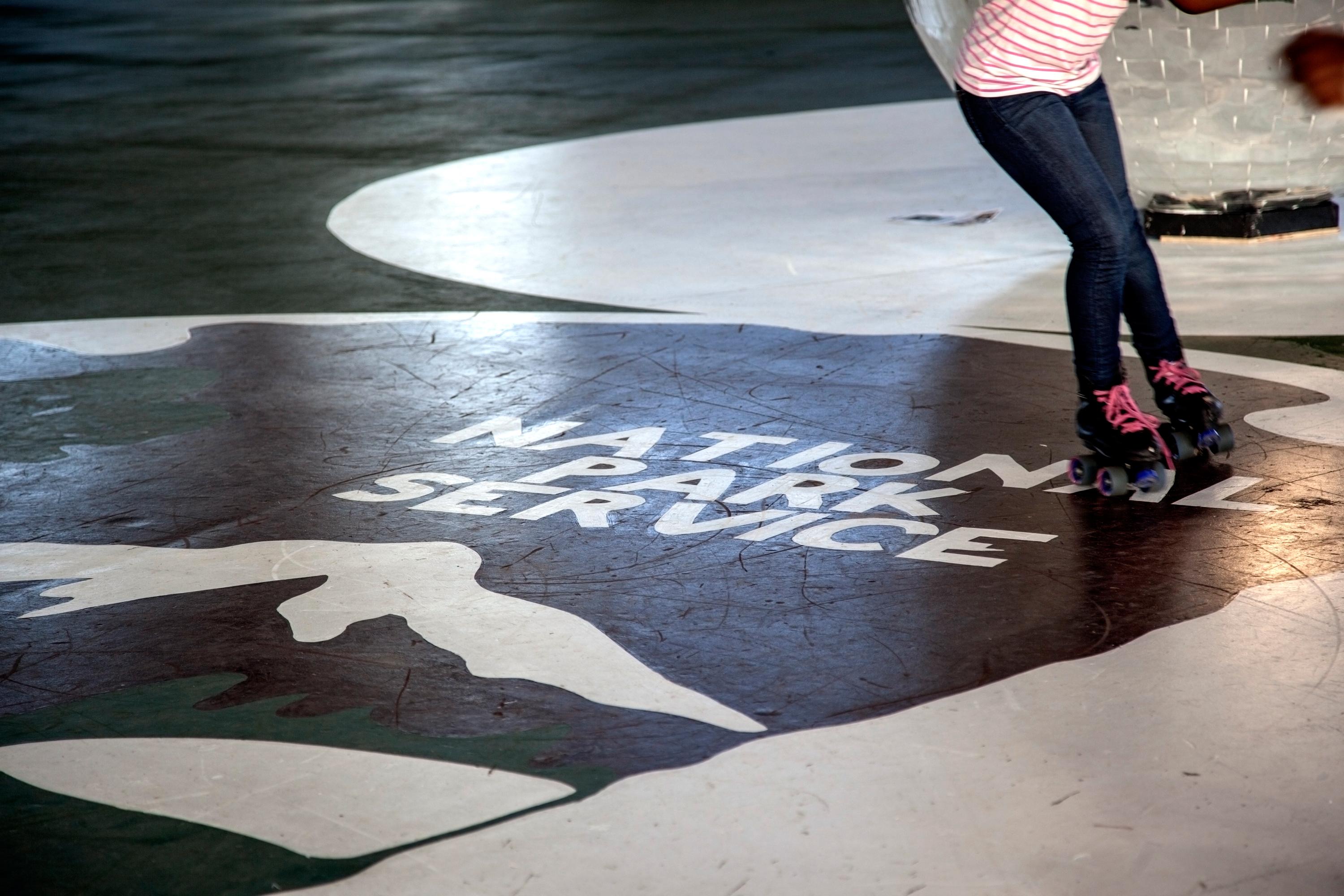 A girl skates over a National Park Service logo.