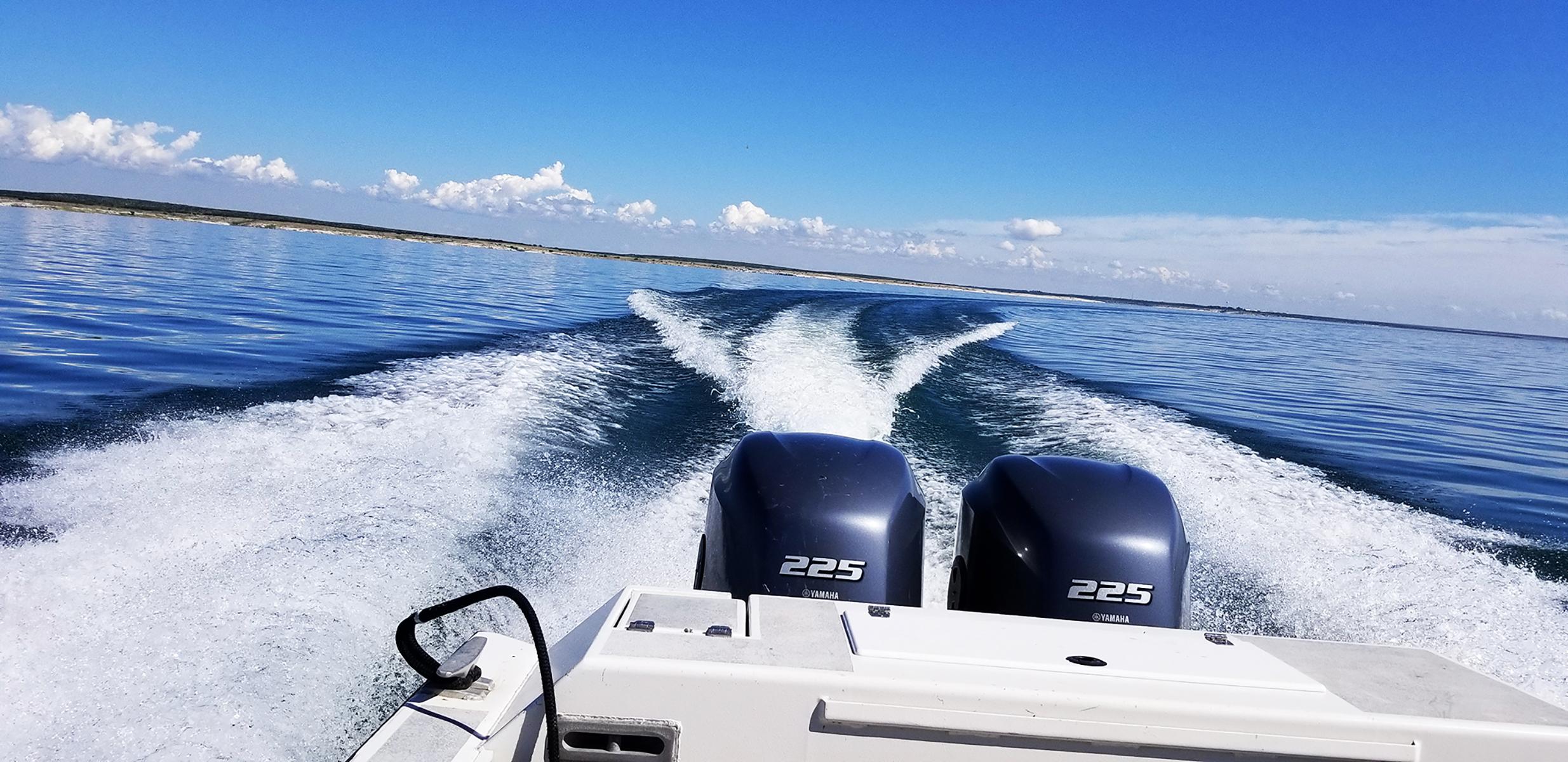 Back of motorboat looking out toward the horizon showing a banking turn to the starboard side.