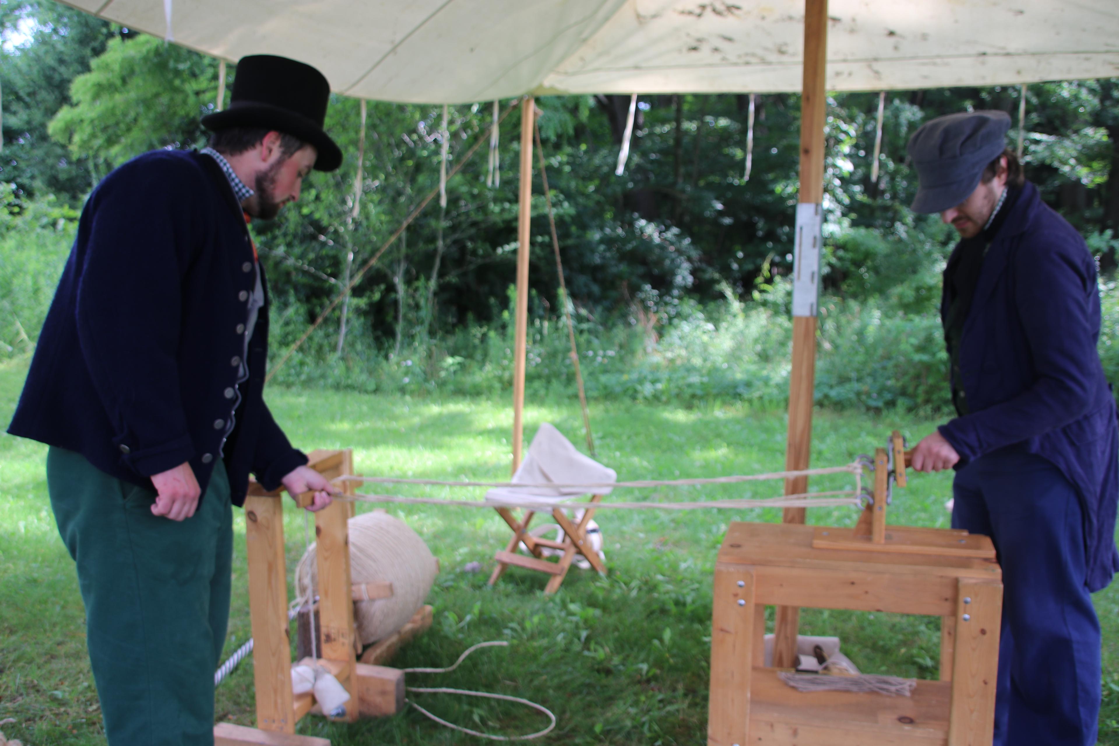 Two rangers in period clothing doing a rope making demonstration.