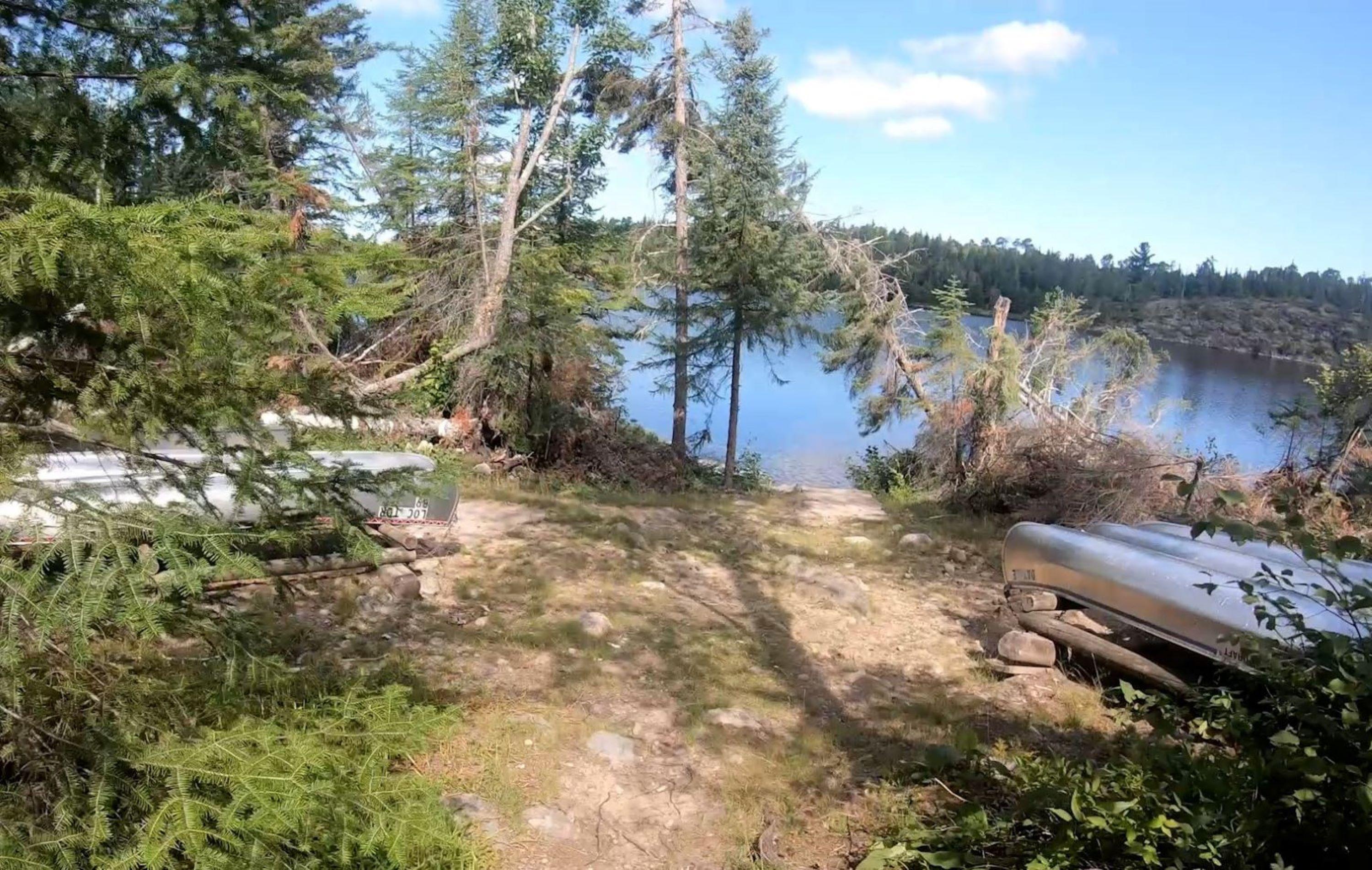 View of Locator Lake Trailhead at Locator Lake with Interior Lake Canoes next to shore.