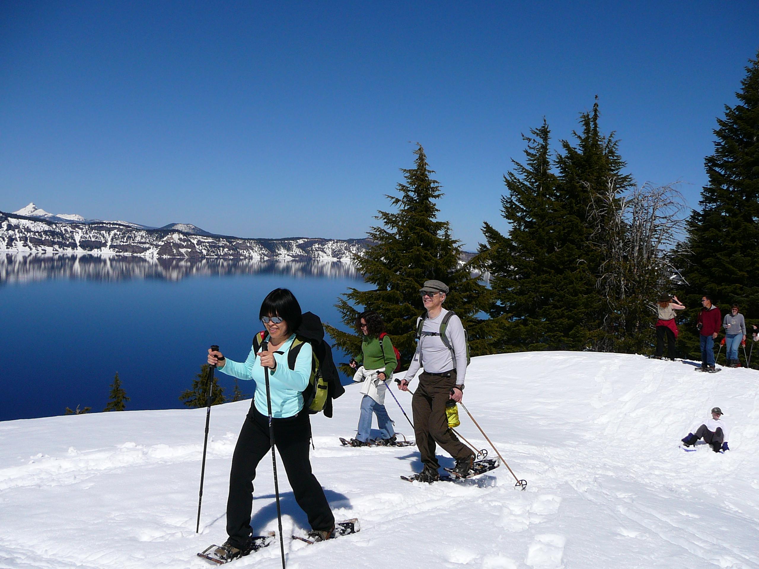 People snowshoeing with Crater Lake in the background.