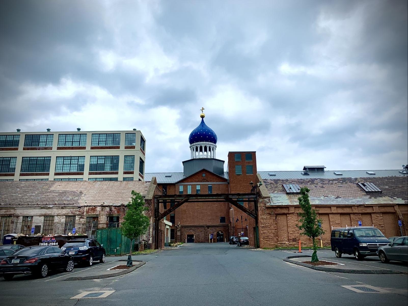 The Colt Dome between the two brownstone buildings on a cloudy day