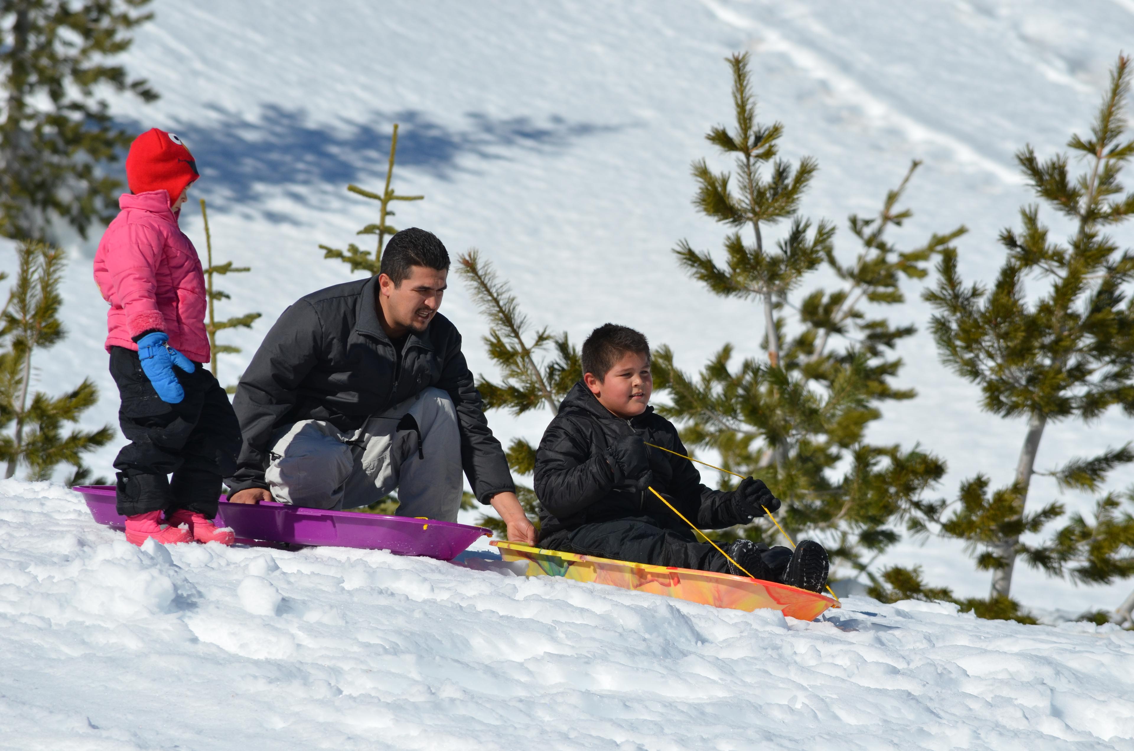 a family preparing to sled down a snowy hill