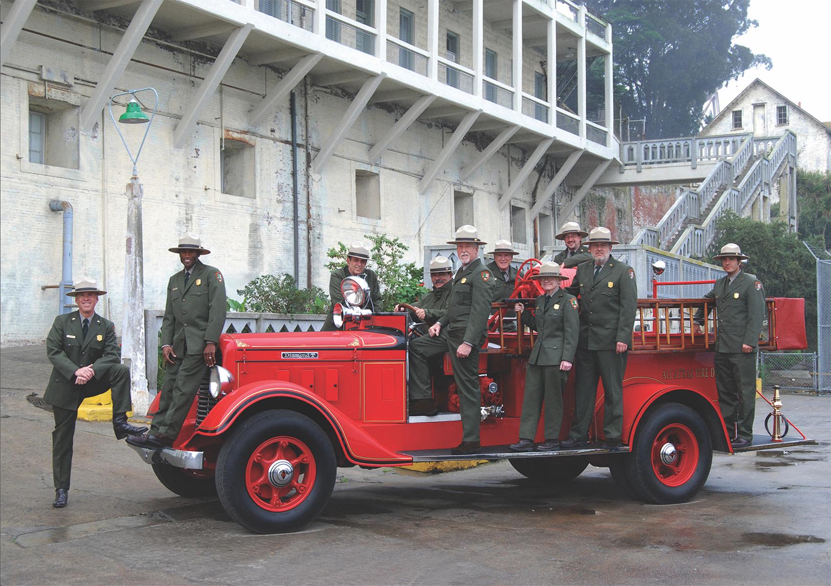 Parks Rangers standing on and around a red fire engine.