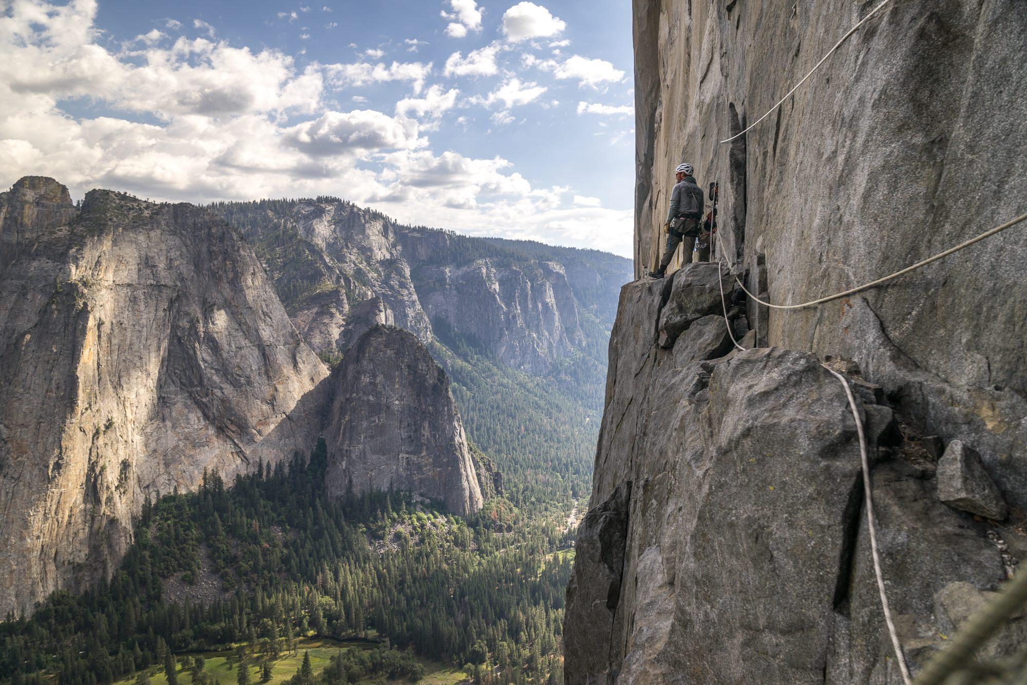 Climber on ledge on rock face with ropes in Yosemite Valley