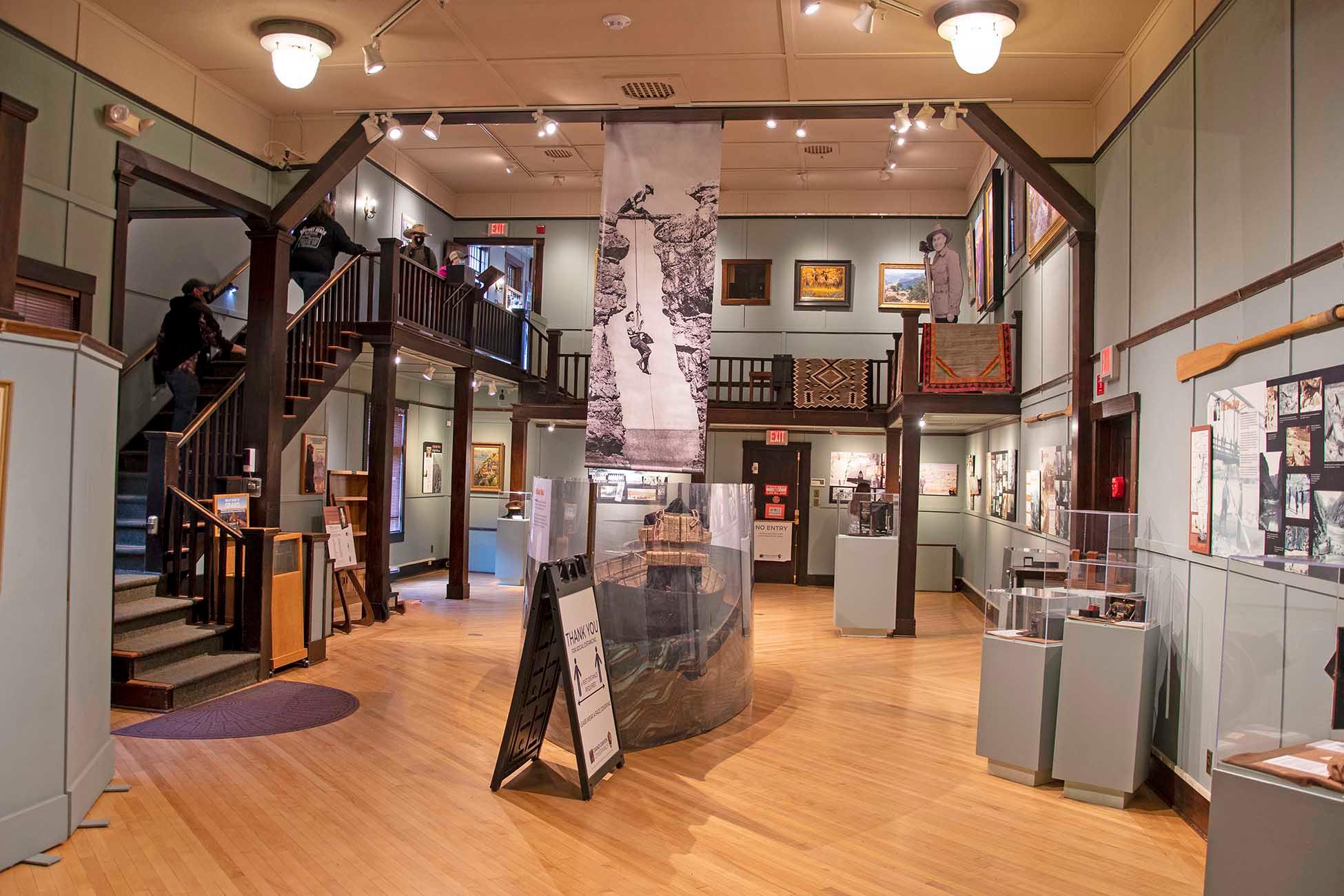 interior of an exhibit hall with a stairway descending from the second story.