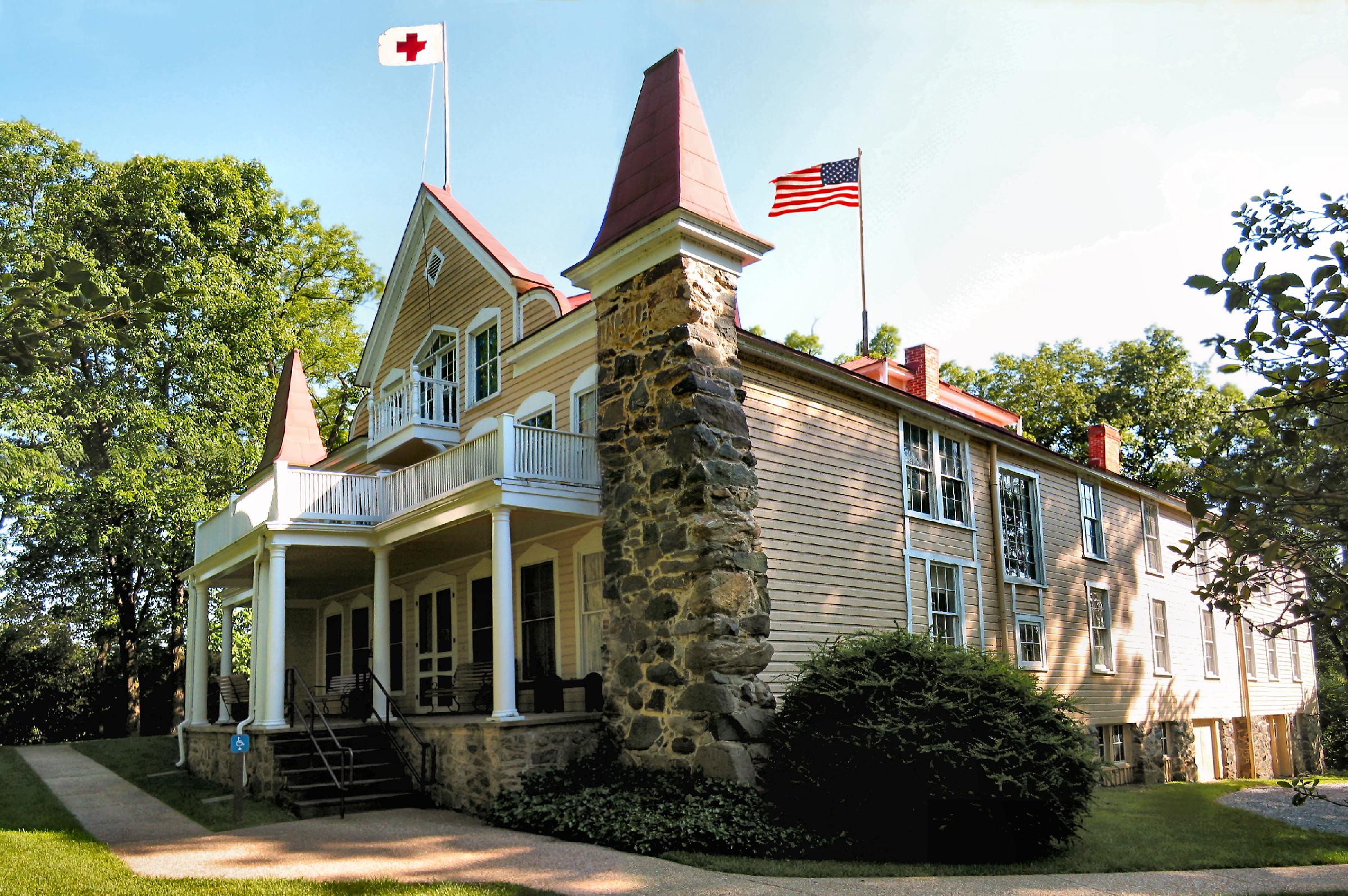 A large Victorian home with Red Cross flag flying at the top.