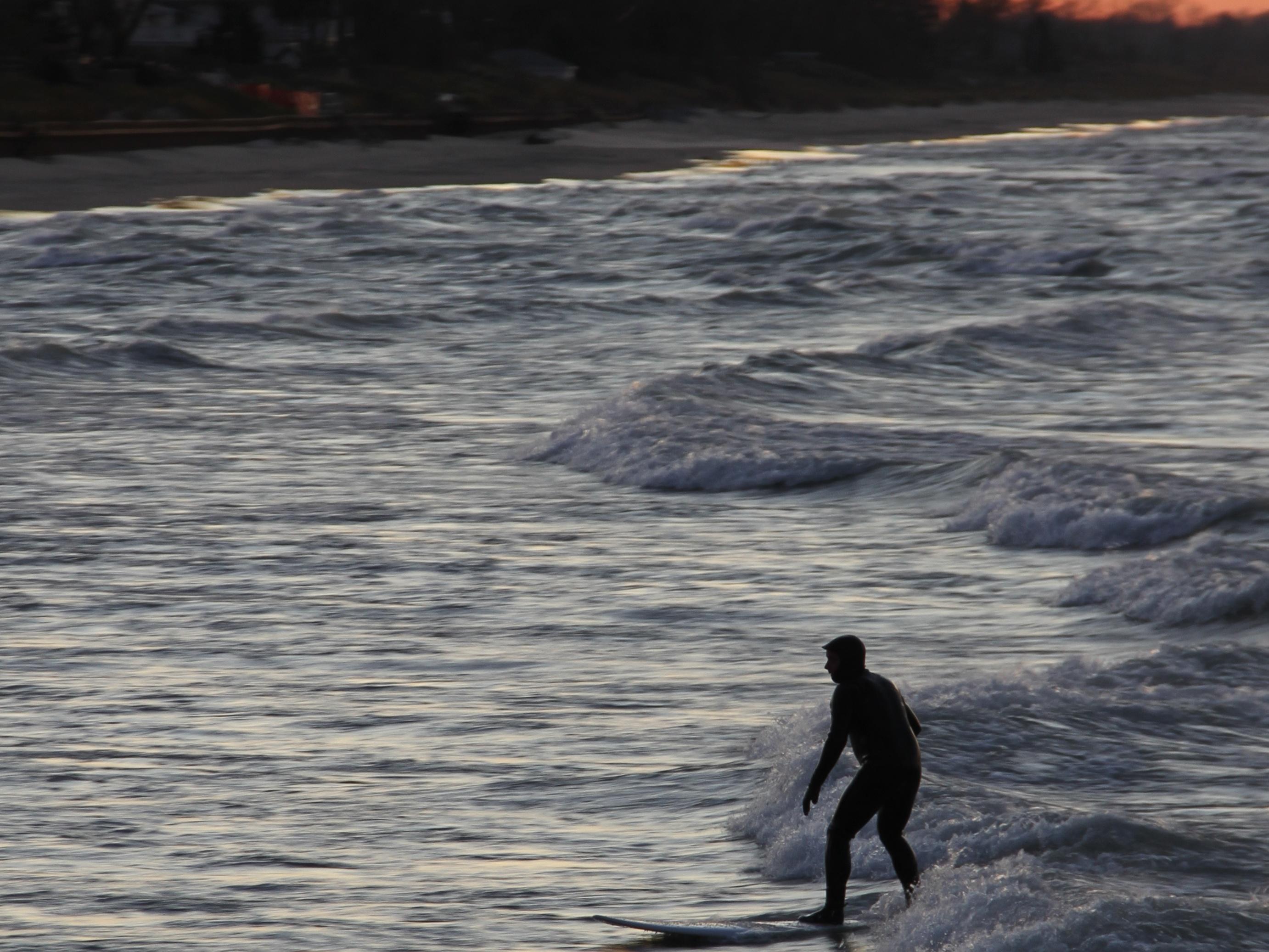 Person surfing the waves around sunset at Portage Lakefront and Riverwalk.