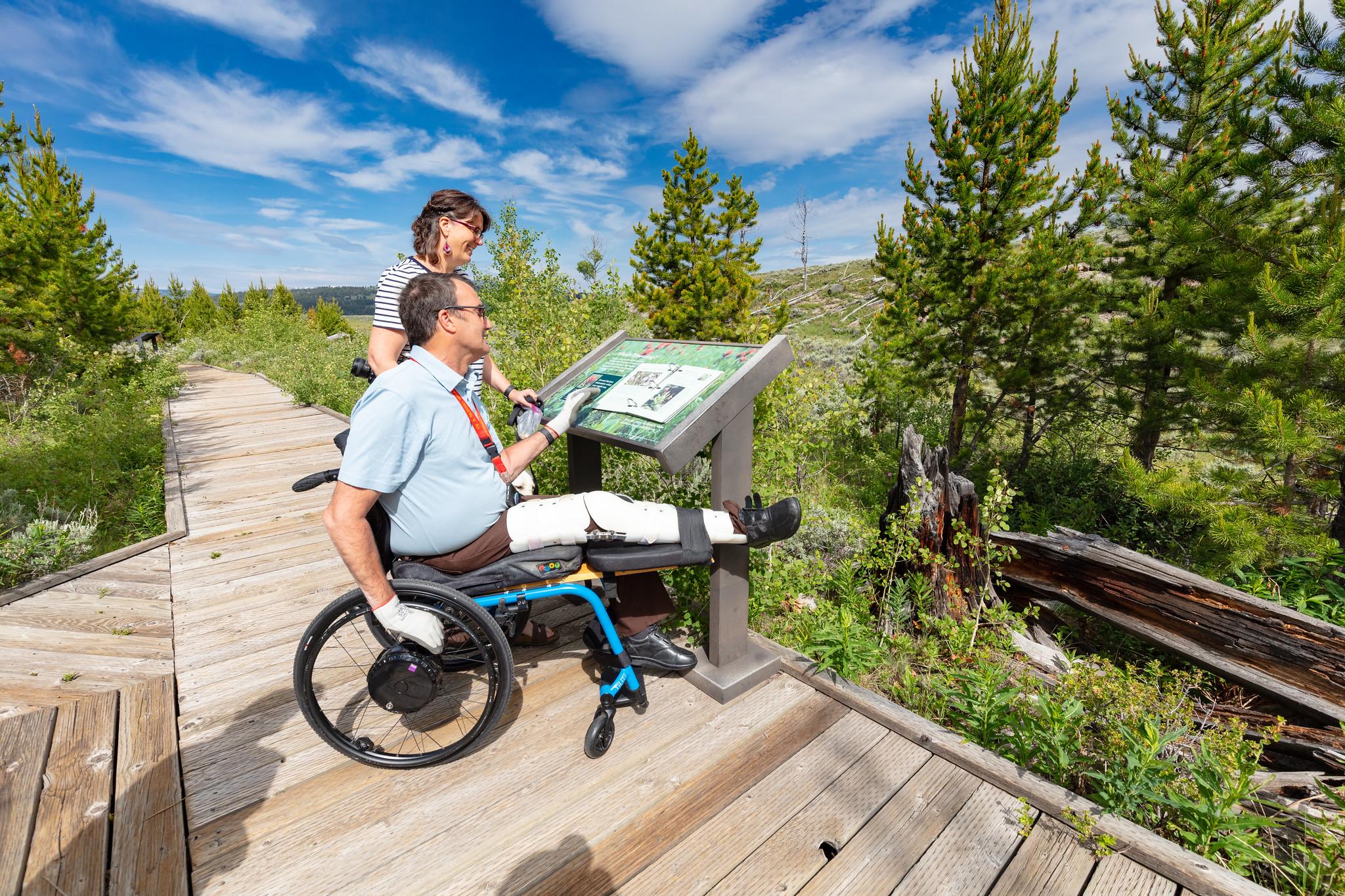 Visitors on a boardwalk view a low profile wayside exhibit