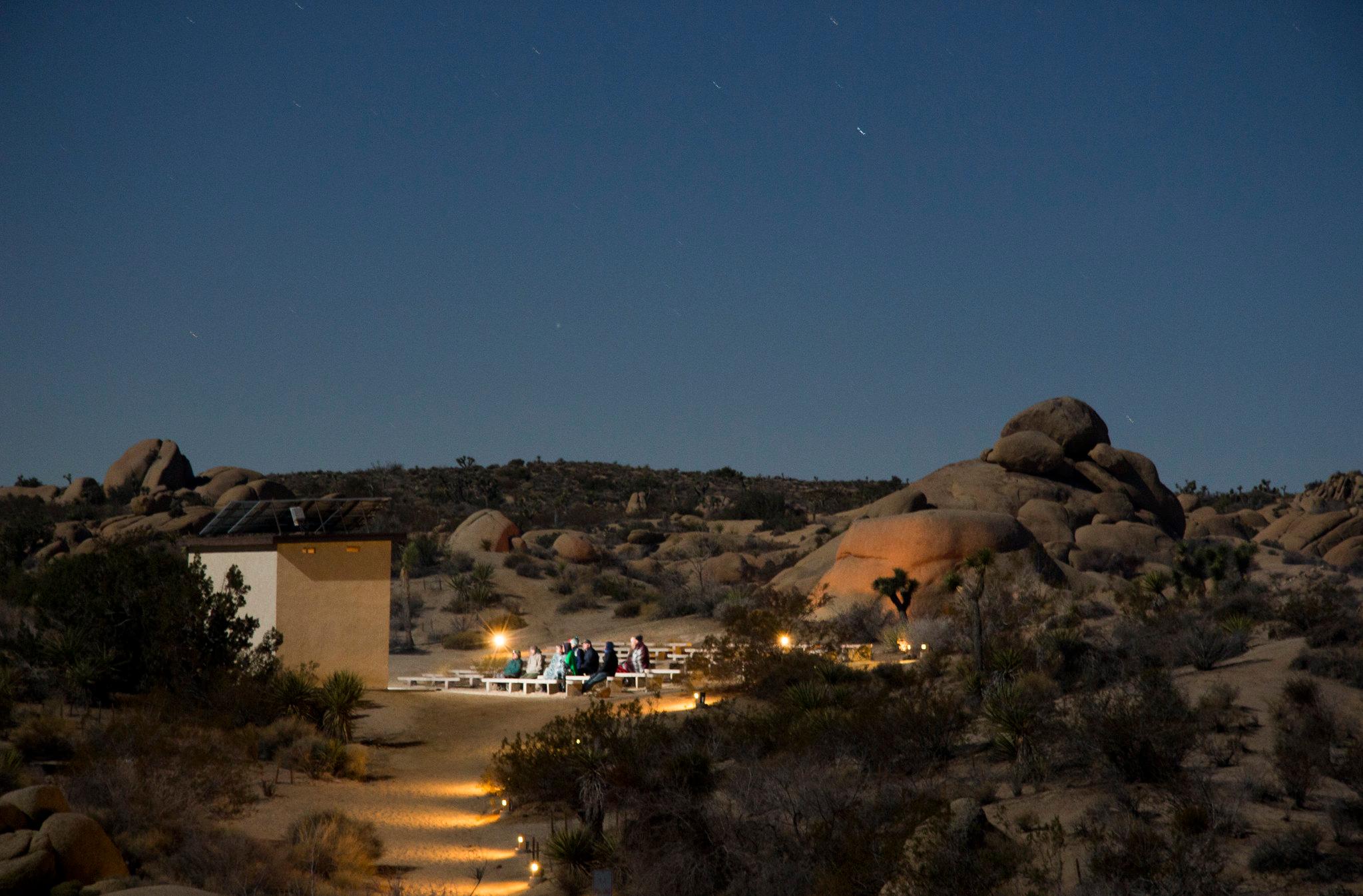 A small amphitheater is surrounded by boulders and desert shrubs.