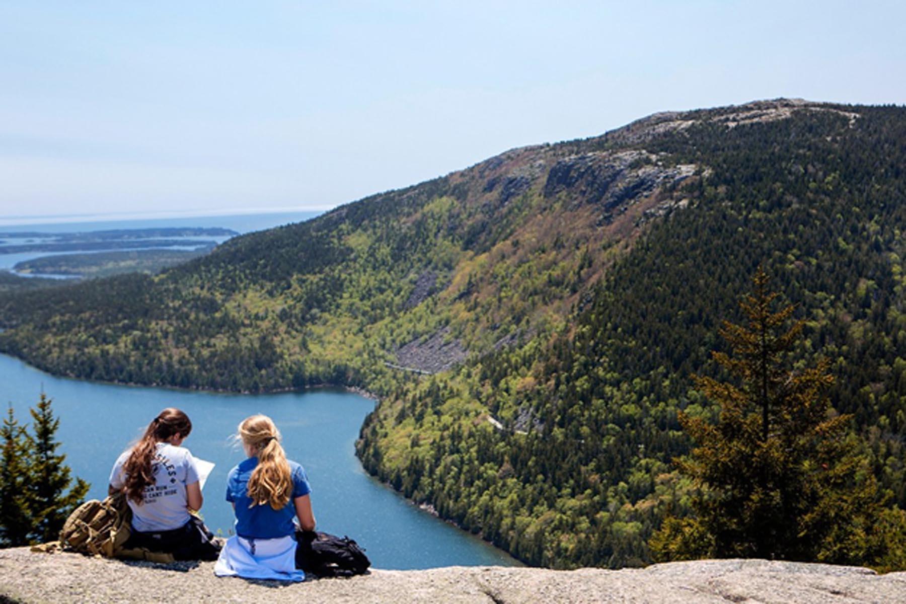 Two hikers sit on the bald granite summit of North Bubble studying a map.