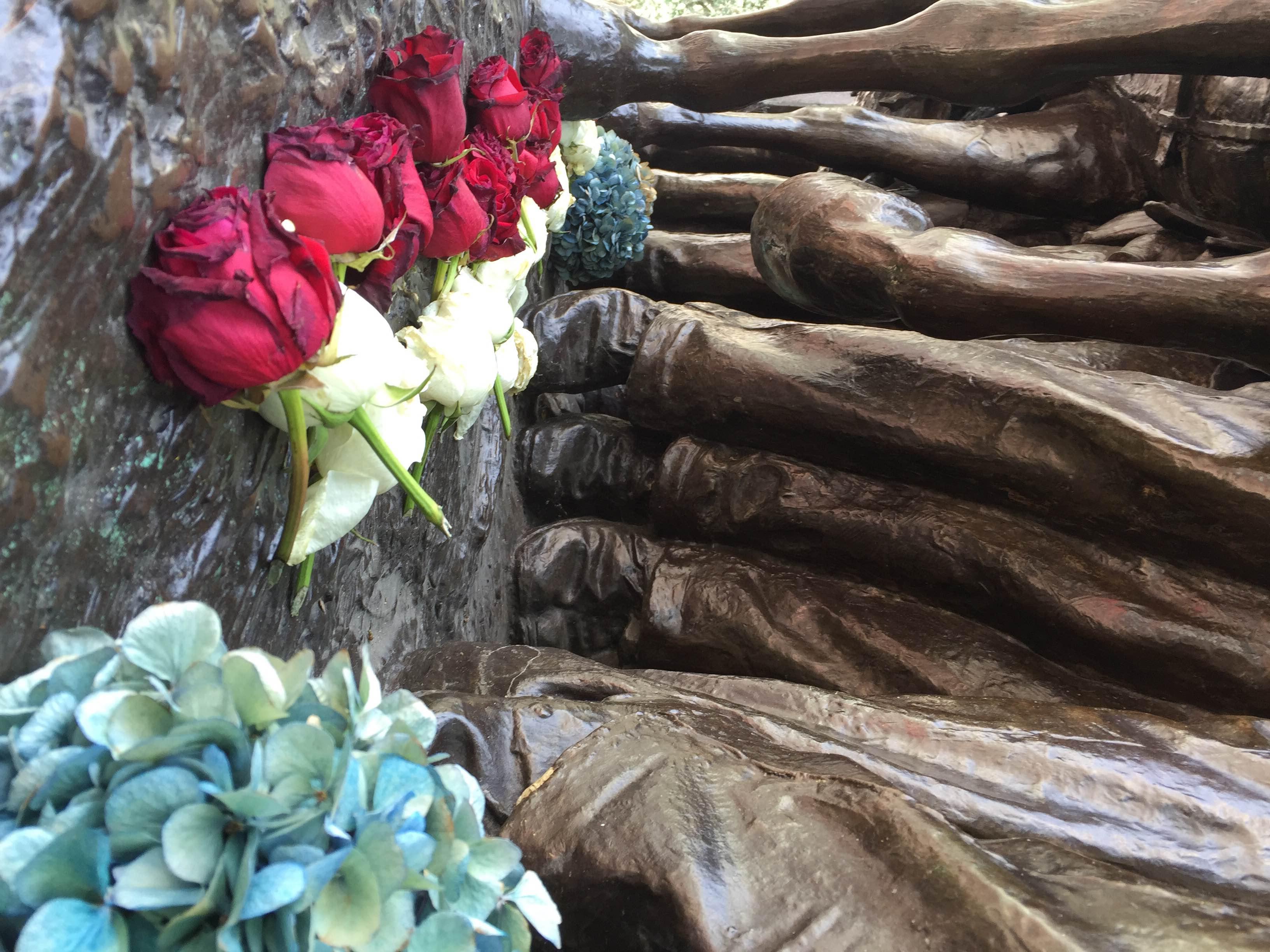 A close up image of flowers laid at the feet of the soldiers on the Shaw Memorial