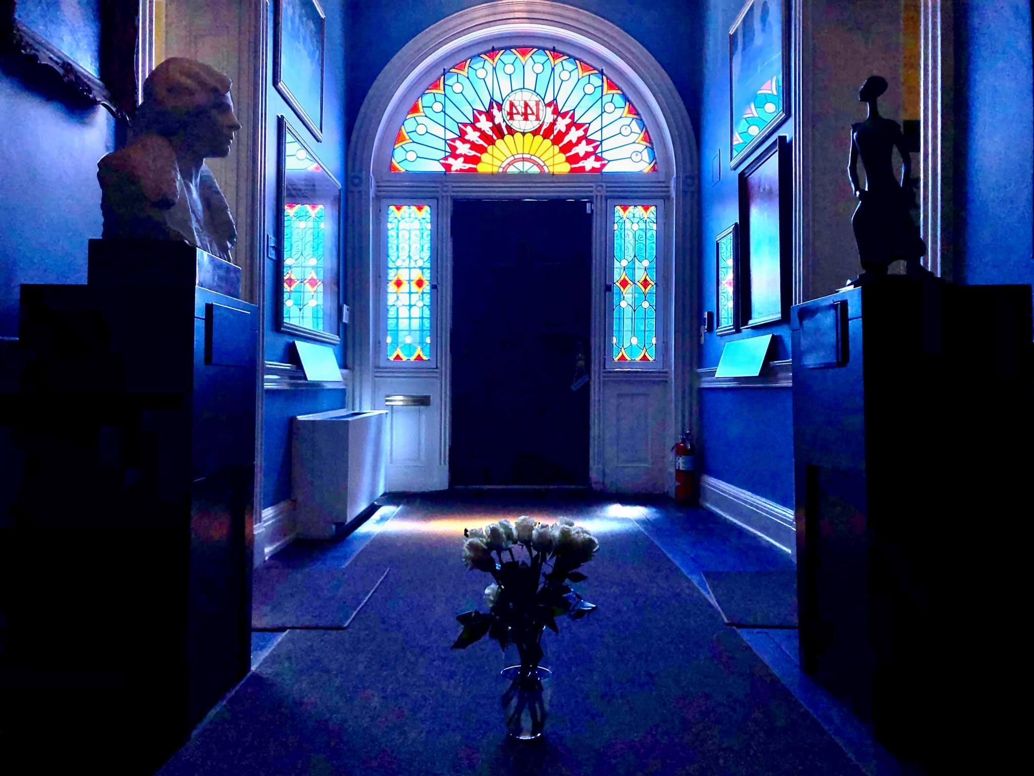 Interior photo of the Hall of Portraits lit by sunlight streaming through stained glass