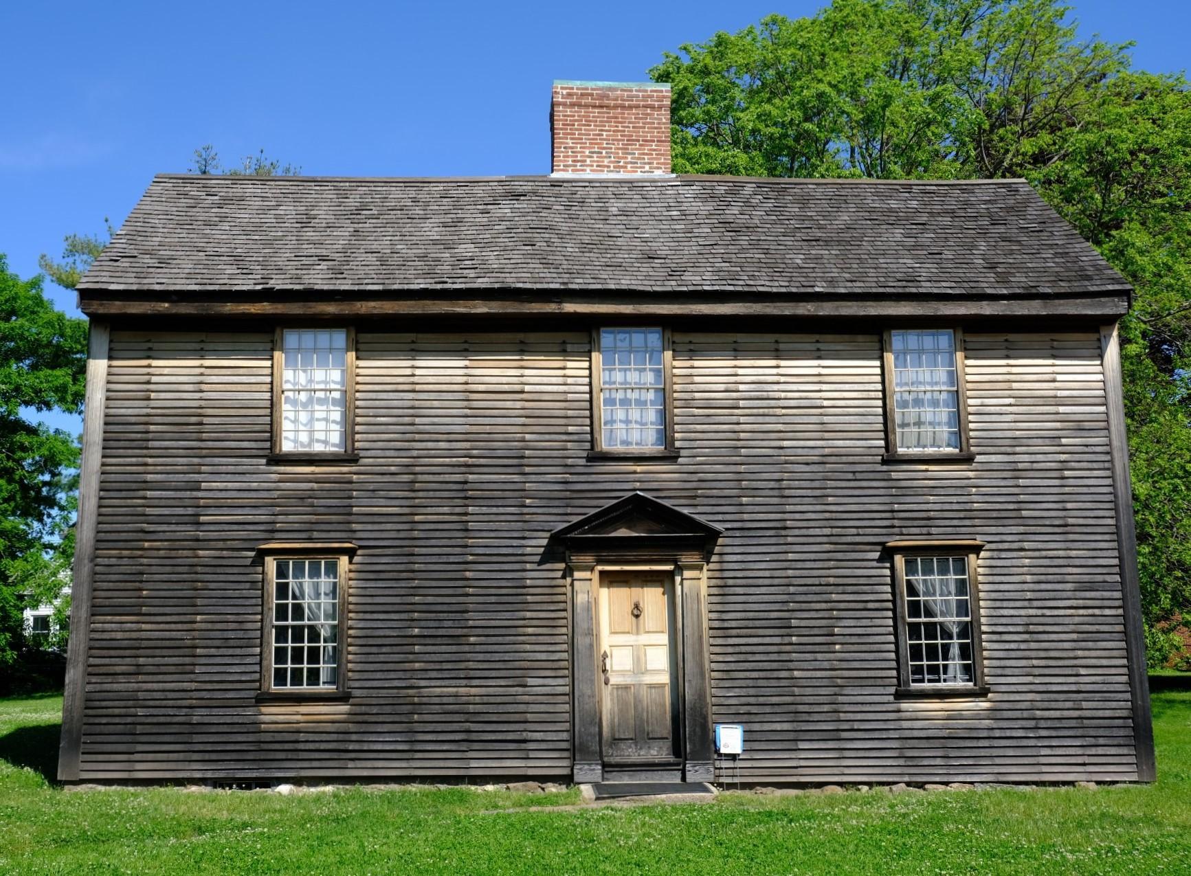 A New England "salt-box" style home with wooden siding and trim.