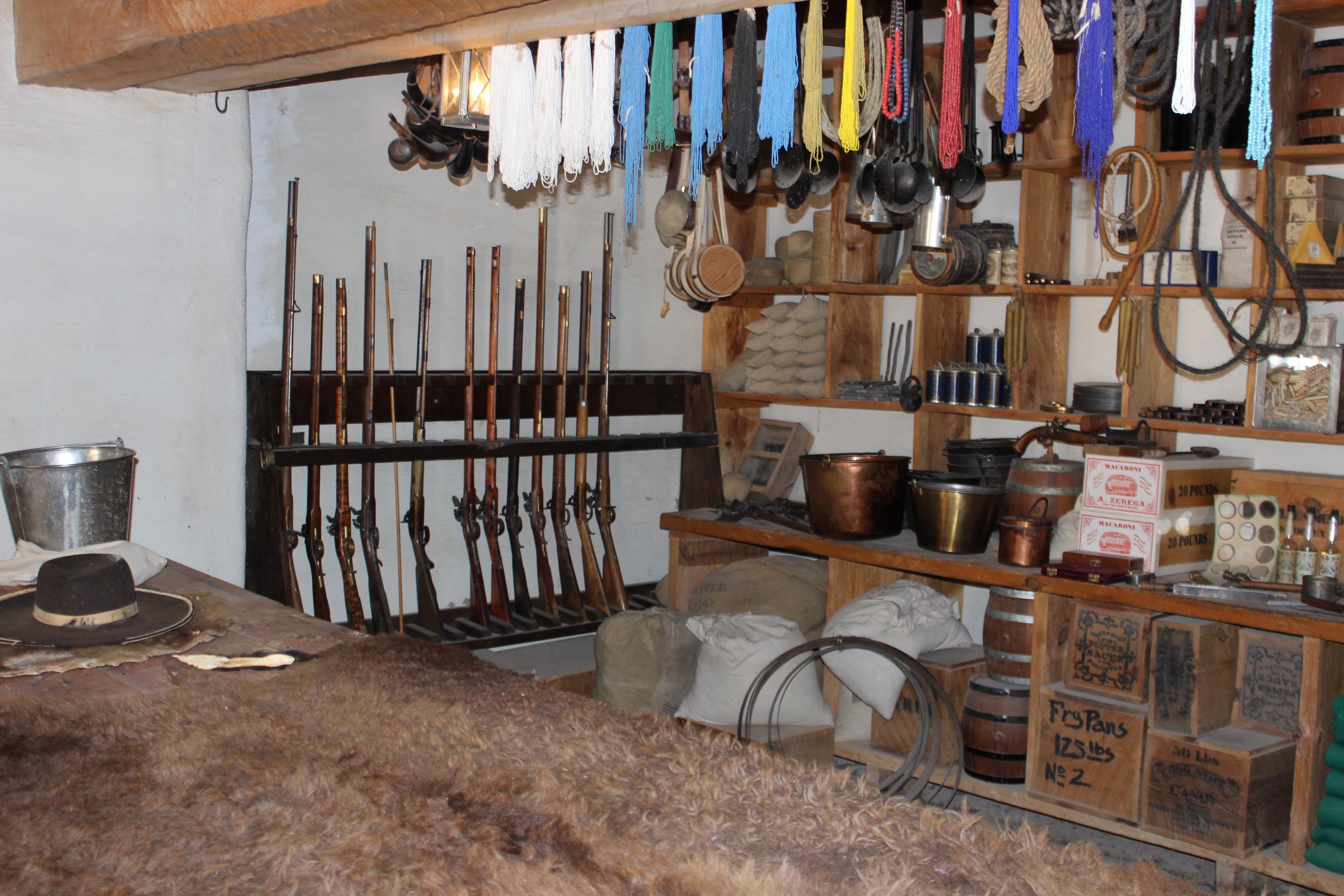 A wooden counter is in the foreground of a trade room, with sales items on display in the background