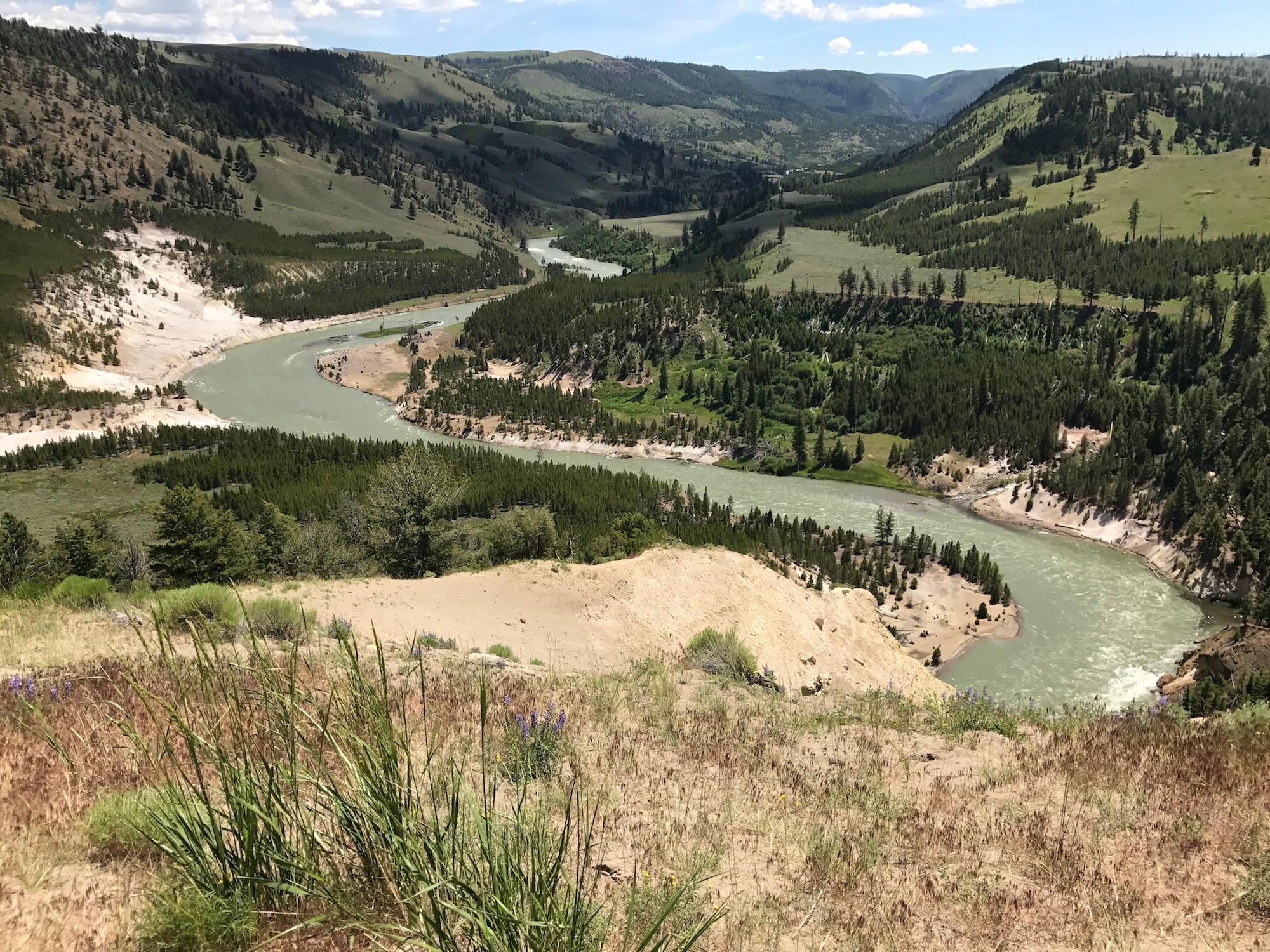 A greenish river meanders through a hilly river valley.